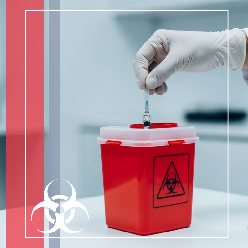 Grand rapids sharps img1 gloved hand safely disposing of a syringe into a red sharps container in a clinical setting